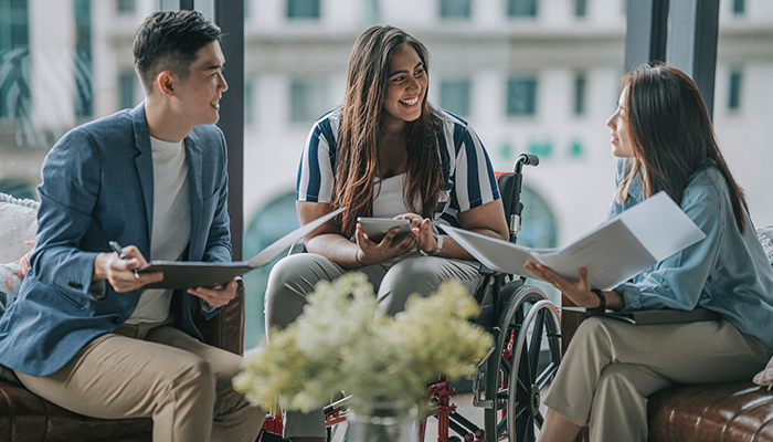 Gruppo di persone con background diversi e con disabilità che si confronta all’interno di spazi aziendali.