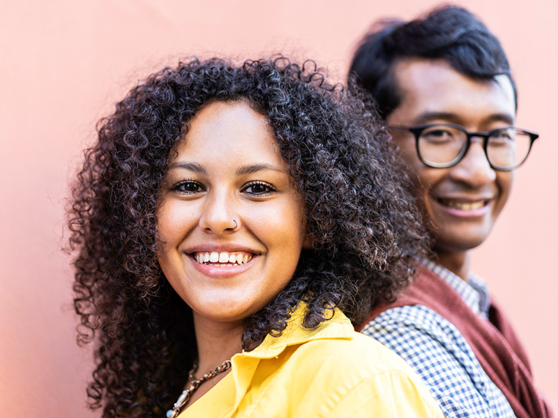 Primo piano di una donna e un uomo di background culturali diversi che sorridono.